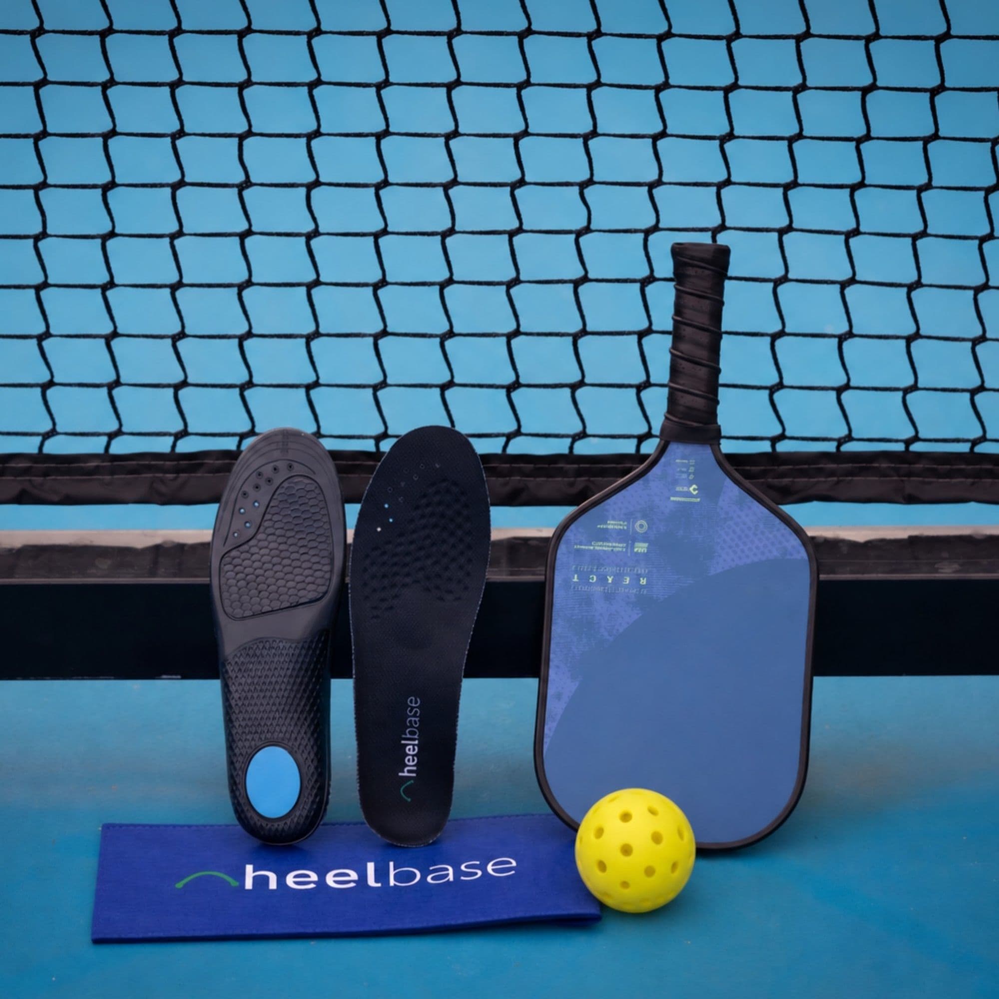 HeelBase Stance insoles displayed with a pickleball paddle and ball courtside