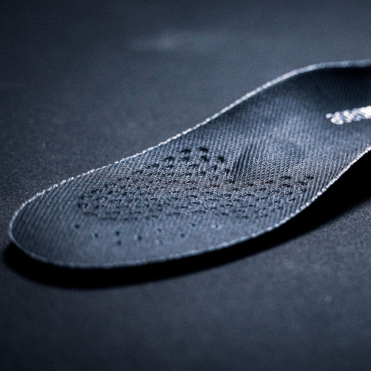 Angled close-up of the textured, perforated top sheet on a HeelBase Stance insole