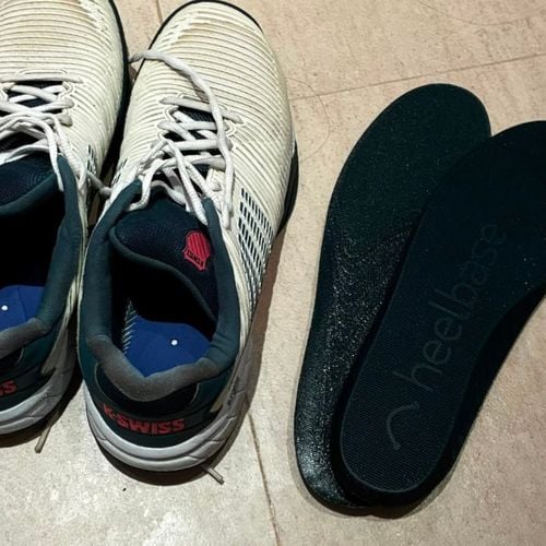 Customer photo of a pair of HeelBase Drive insoles next to court trainers