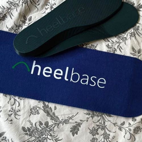 Customer photo of a pair of HeelBase Drive insoles on the bed with the pouch