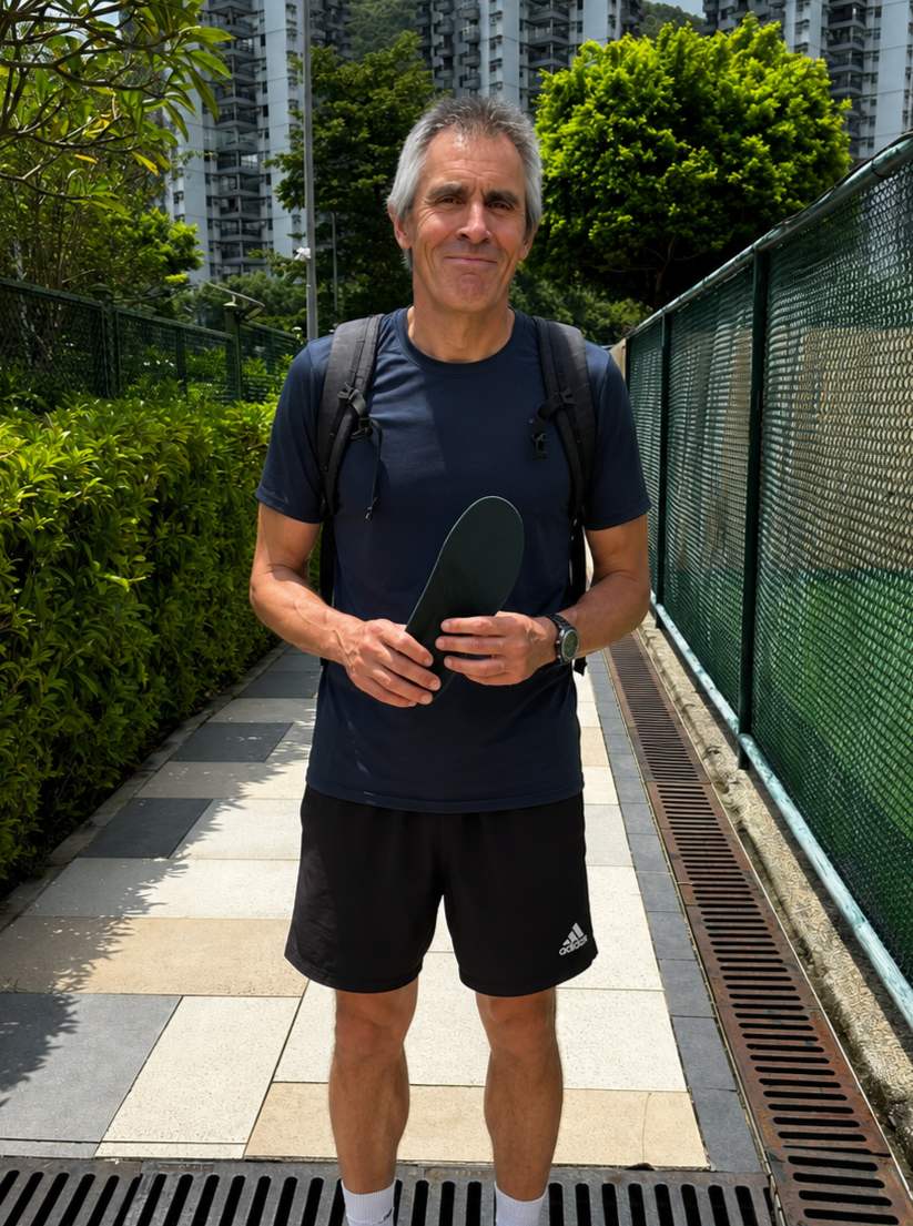 Rob holding a HeelBase Drive insole beside an outdoor pickleball court