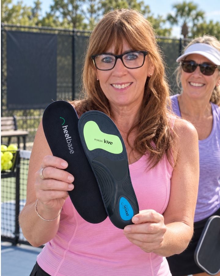 Sheena holding HeelBase Apex insoles beside a pickleball court.
